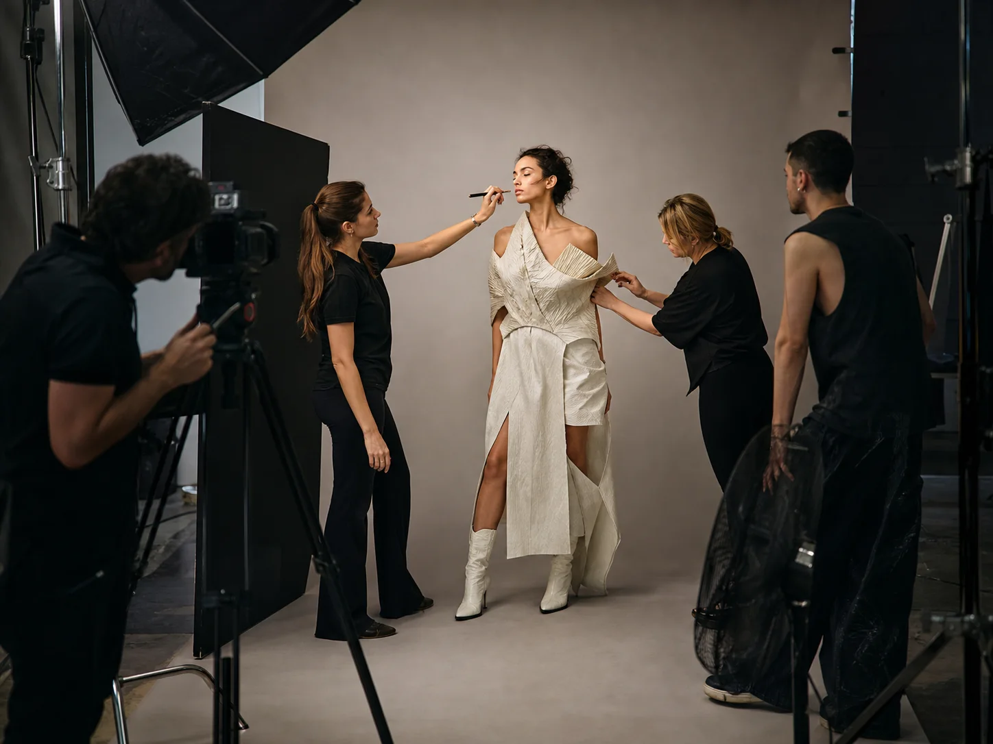 A fashion editorial crew preparing a model on a professional studio set