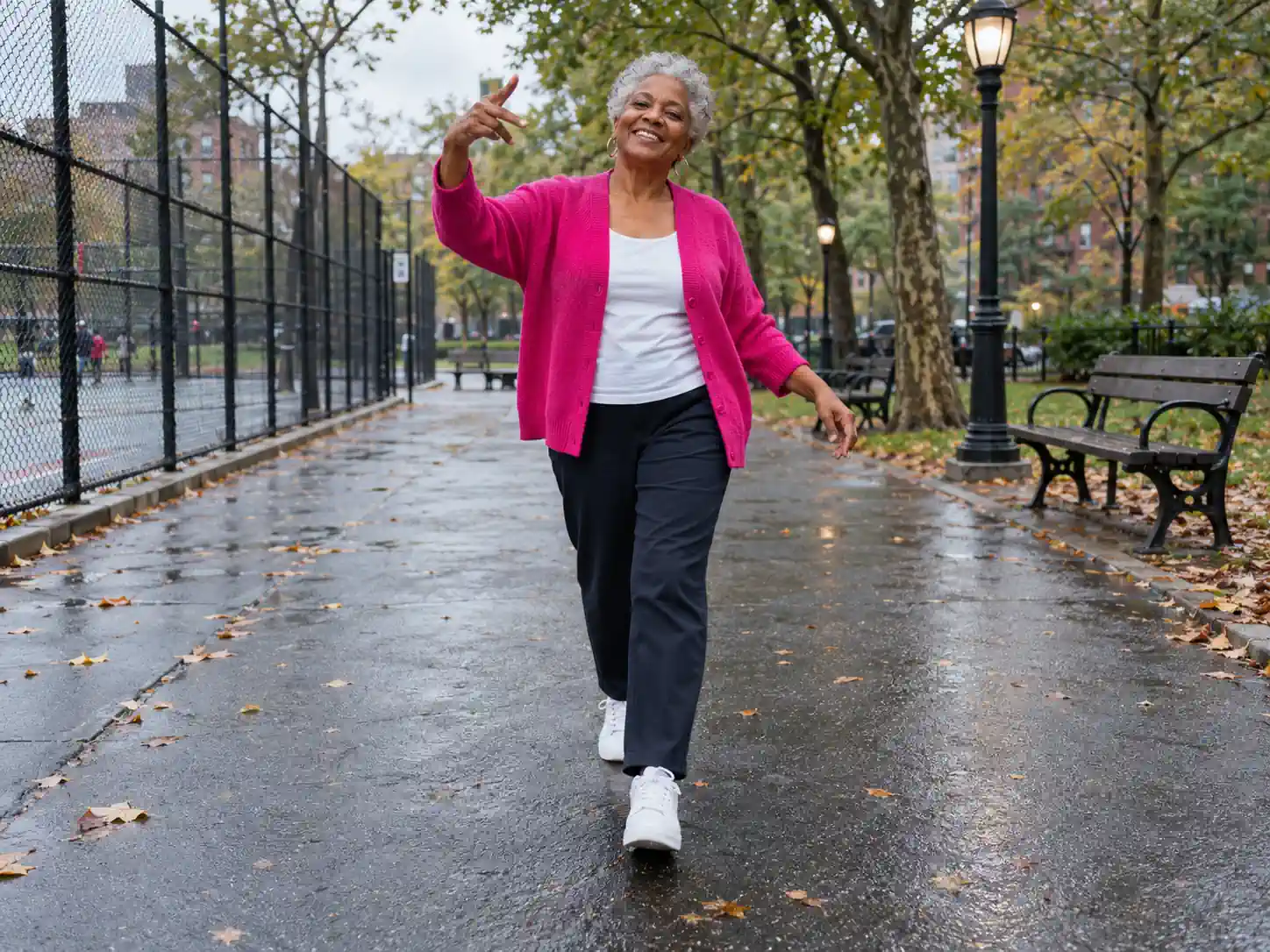 A smiling grandmother in a bright cardigan doing the swagger walk with one arm raised in a city park, a Fergie Baby AI video